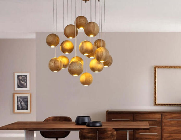 Nordic wood ball chandelier hanging above a dining table in a stylish interior, providing warm light.